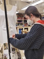 A student pins an element on a gown in the costume studio