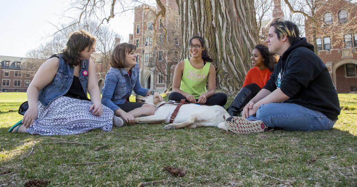 Lucy Sidi &#039;18, Deqa Aden ’18, and Leina’ala Voss ’18 sit under a tree with Lucy&#039;s service dog and two friends