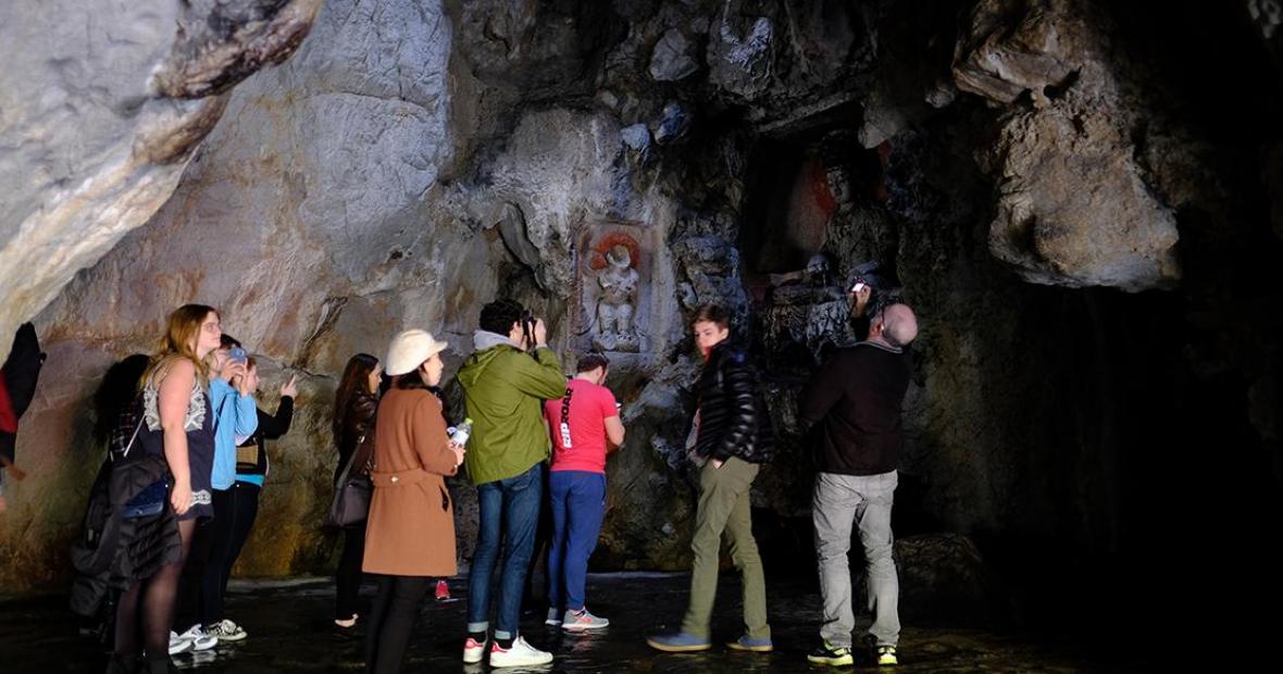 Group looking at small figure carved into a niche in a grotto wall