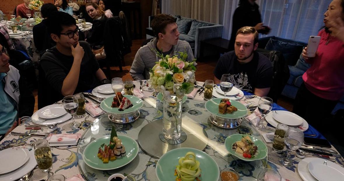 Group sits at round table set with fine dishes