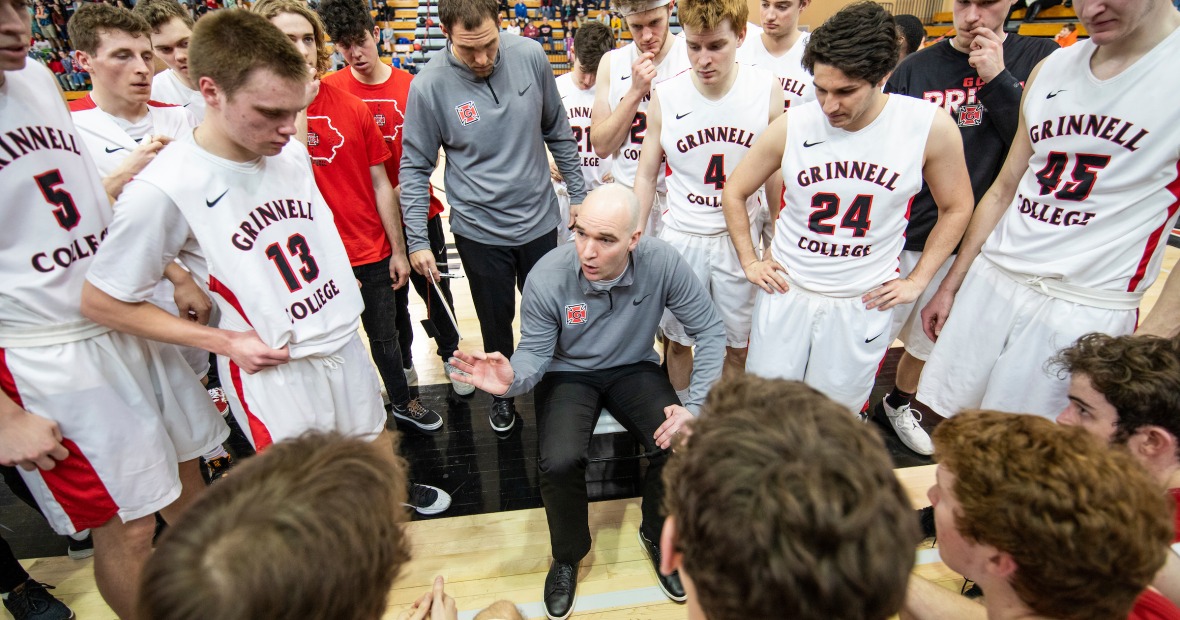 Head coach David Arseneault Jr. talks with the men's basketball team during a timeout.