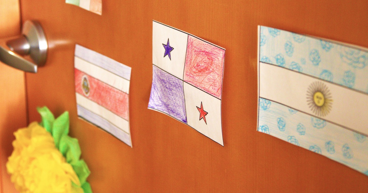 Three Latin flags are taped next to a doorknob and a paper-made flower