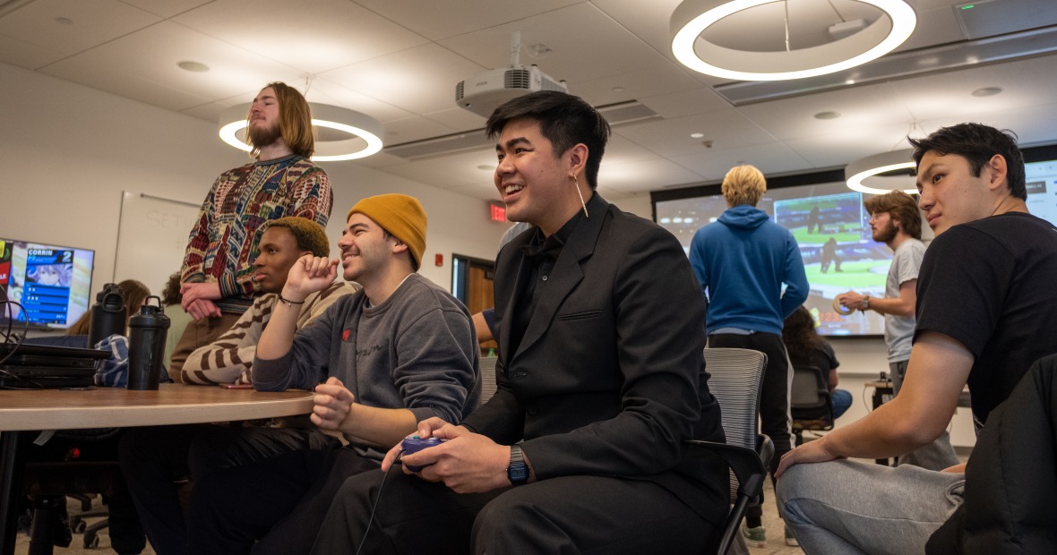 Prommolmard and other students hold controllers in a classroom, playing video games.