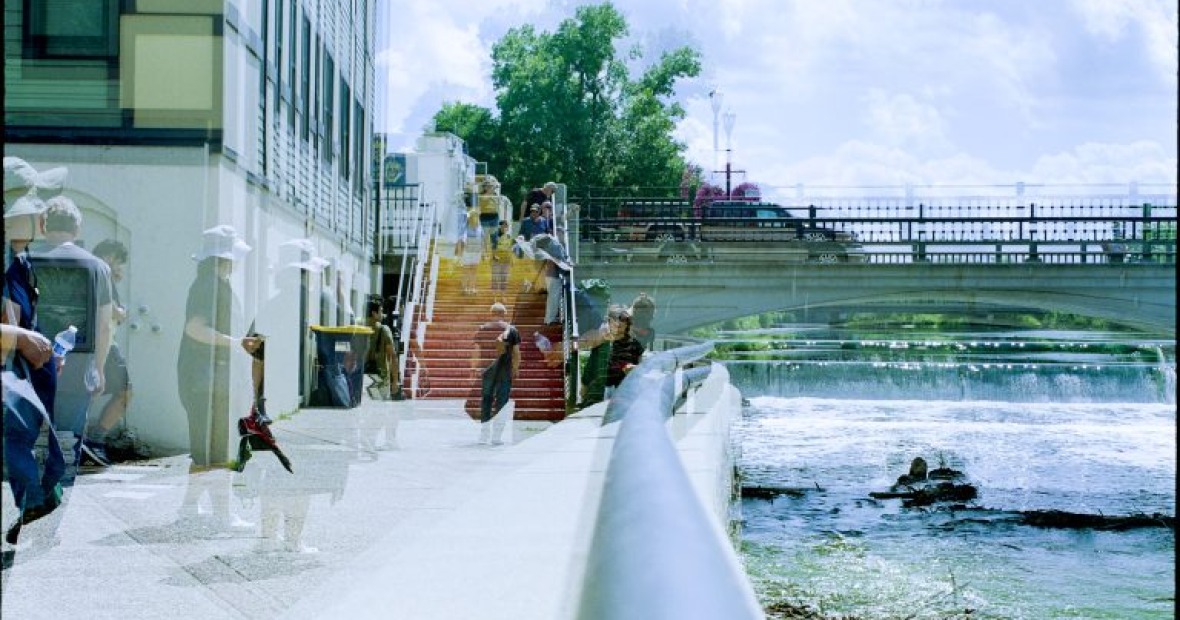 A saturated image of an outdoors scene. There isa bridge and a staircase. You can see transparent images on people throughout the image.
