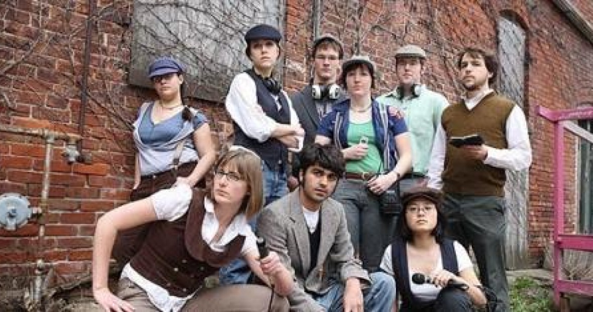 The Listen Hear staff, dressed as old-timey newsboys, pose with audio equipment.