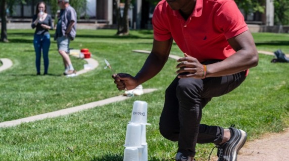 Student attempts to build plastic cup tower
