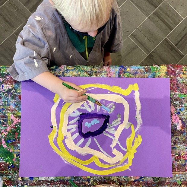 Overhead view of a child painting a flower