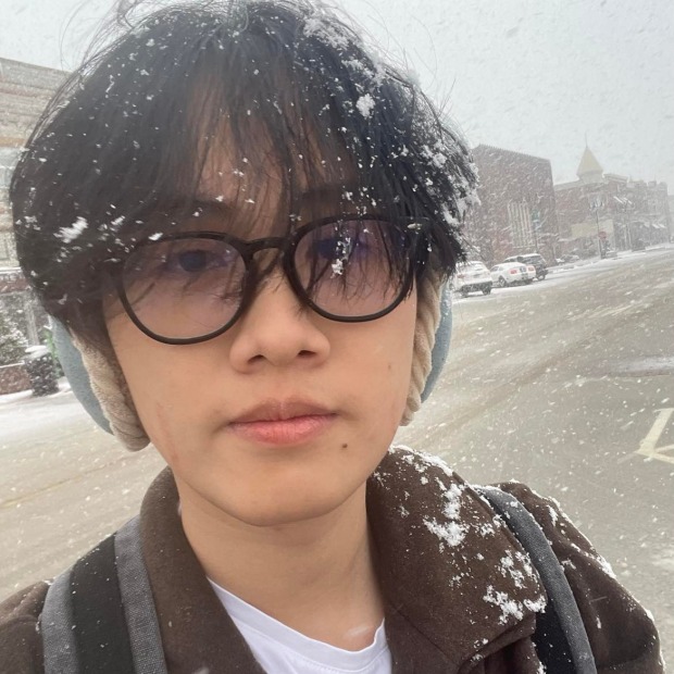 Huy Nguyen '25 standing in downtown Grinnell while it snows 
