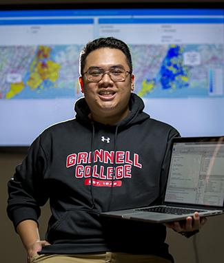 Jarren Santos holds his laptop with digital maps appearing behind him