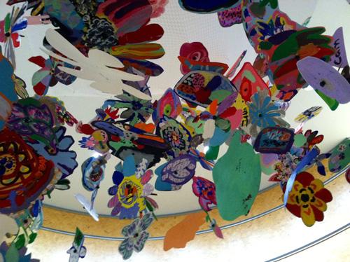 Colorful paper and paint flowers suspended from ceiling 