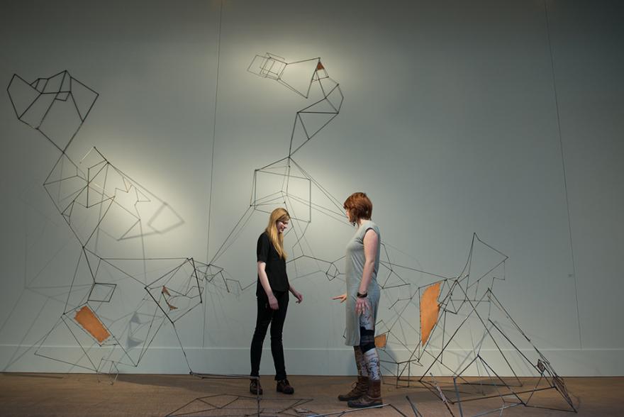 Two students admiring wire art sculpture