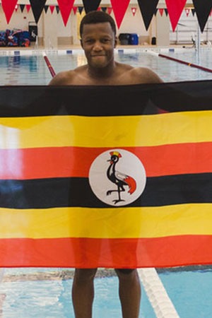 Joshua Tibatemwa ’19 in Grinnell’s natatorium holding Ugandan flag