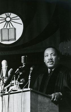 Rev. Martin Luther King Jr at lecturn with stained glass window behind him