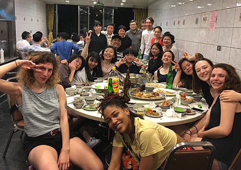 Large group of students, faculty, and collaborating actors sit around a table at a restaurant in Taiwan