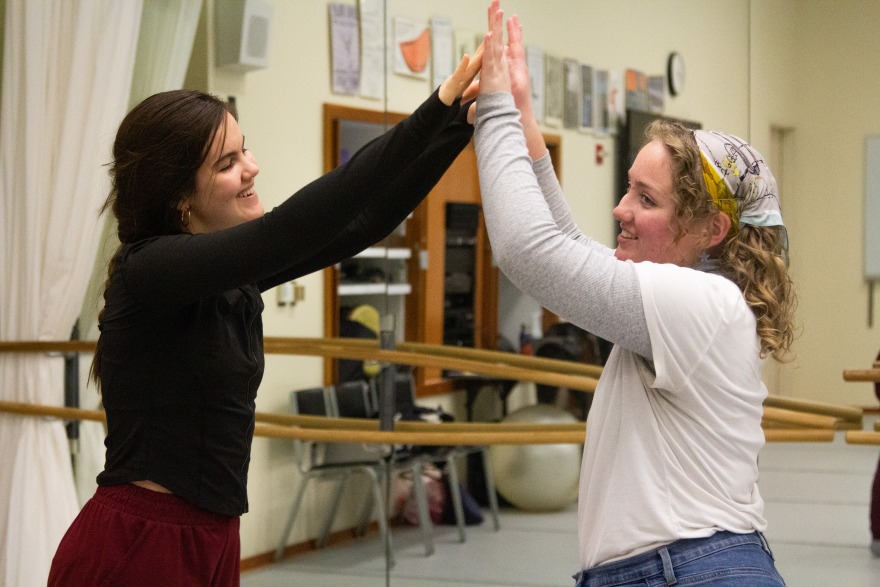 Two students raise their arms hand-in-hand to dance