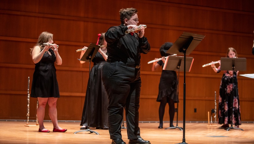 A small group of flautists performs onstage