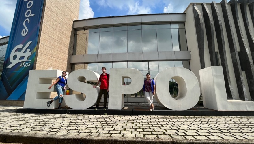 The statuesque metal letters spelling ESPOL are as tall as our three travelers, as they pose on the university campus.
