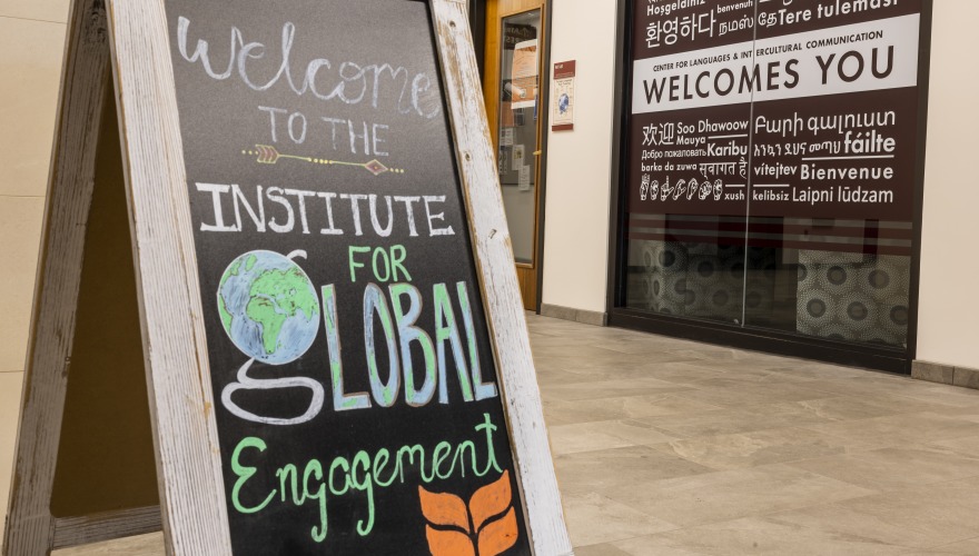 A chalkboard sign that reads, "Welcome to the Institute of Global Engagement," next to a wall that says, "Welcome," but in different languages. 