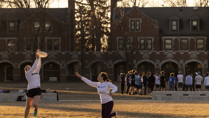 Two young women play Ultimate Frisbee on the Grinnell campus