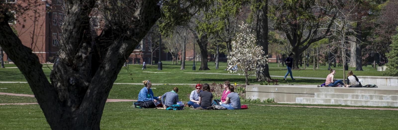 A group of students sits in the grass in central campus