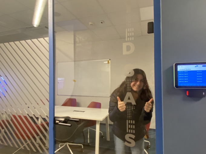 Vanessa stands in front of a transparent glass door with the words "United States" on it