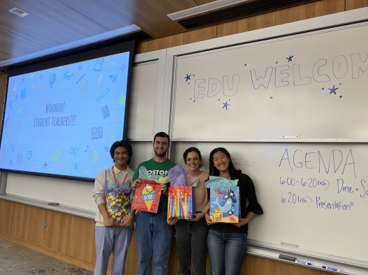 A power point slide with the words: "Woohoo! Student teachers" sits left of the student teachers. The student teachers smile with gifts in their hand