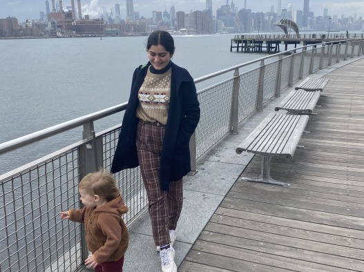 Vanessa and her Brooklyn extern host's baby look over the ocean as they stand at a boardwalk