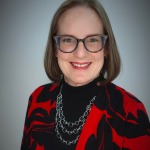 Headshot of Susan Sanning wearing glasses and a red and black sweater.
