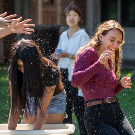 Students in a water fight smiling as they avoid a spash