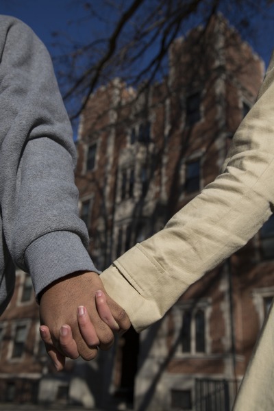 Close-up of the hands as two students hold hands while walking on campus