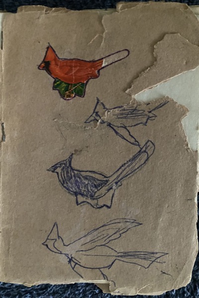 A child's drawings of birds adorn the tattered brown paper cover of a book of poetry