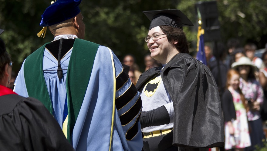 Ethan Chung (class of 2012) shakes hands with Grinnell College President, Raynard Kington, during the 2012 Committeemen ceremony. Ethan is wearing a Batman costume under his graduation robes. 