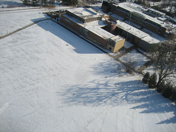 View of Mac field and Rosenfield Center from fairly high. Figures flying the kite are visible, as well as the kite string.