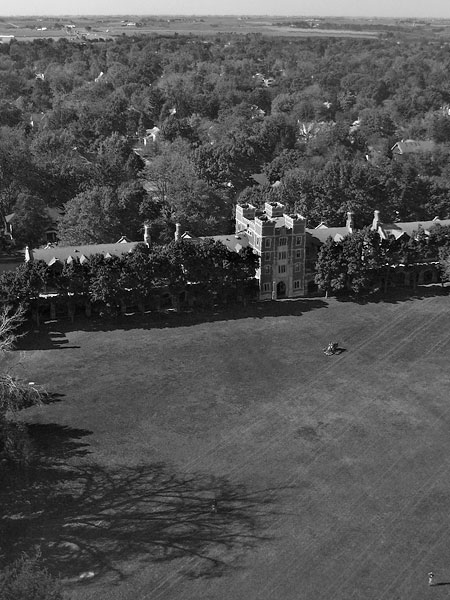 Black and white photo of North Campus and Mac Field from the east. Trees are visible in front of and behind the halls, and the view stretches to the fields in the west.