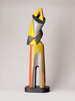 Colorful forms, mostly yellow, black and grey, in a vertical sculpture