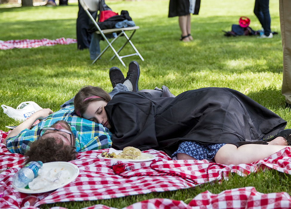 Two people napping on red and white checked picnic blanket