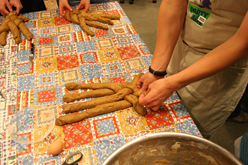 Three loaves being braided, each with four rolls of dough.