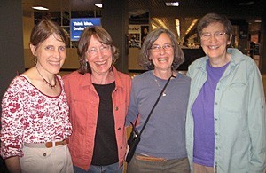 Four women arm-in-arm at an airport