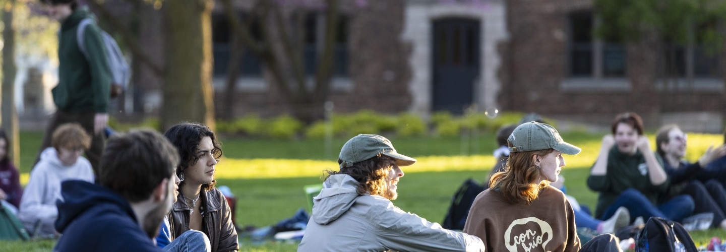 students sit on a lawn in the grass