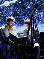 Performers study a chart by a telescope in front of a starry backdrop in Roberts Theatre
