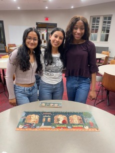 3 students smile in front of a puzzle they've just completed