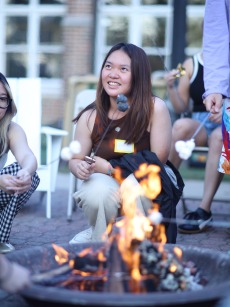 a student roasts a marshmallow outside of south campus at a s'mores event