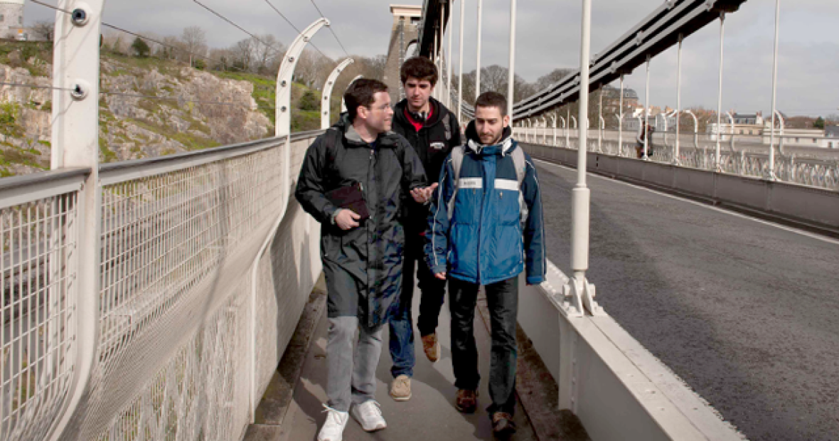 Three students on bridge walkway