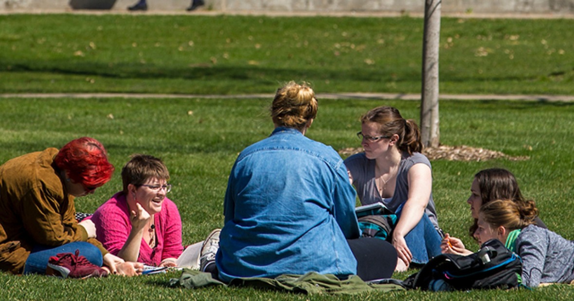 Six students socializing on the grass
