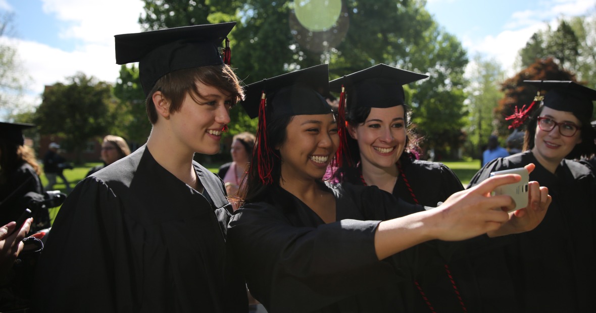 Three graduates in robes taking a selfie before the ceremony