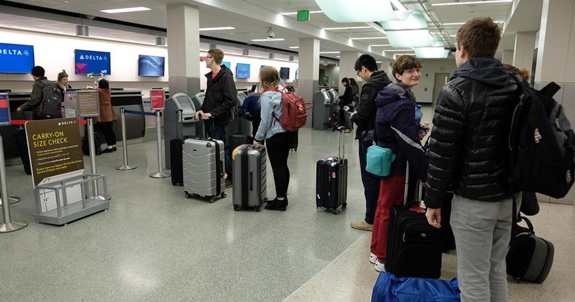 Students with their luggage wait in line to check in at Delta counter