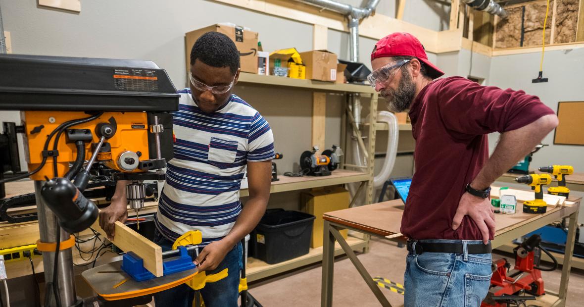 Monty Roper supervises a student with machinery at the maker lab