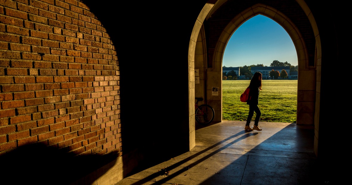 Student passing arches in Gates Rawson Tower
