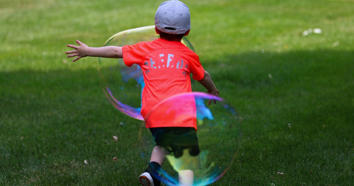Young child chasing large iridescent bubbles