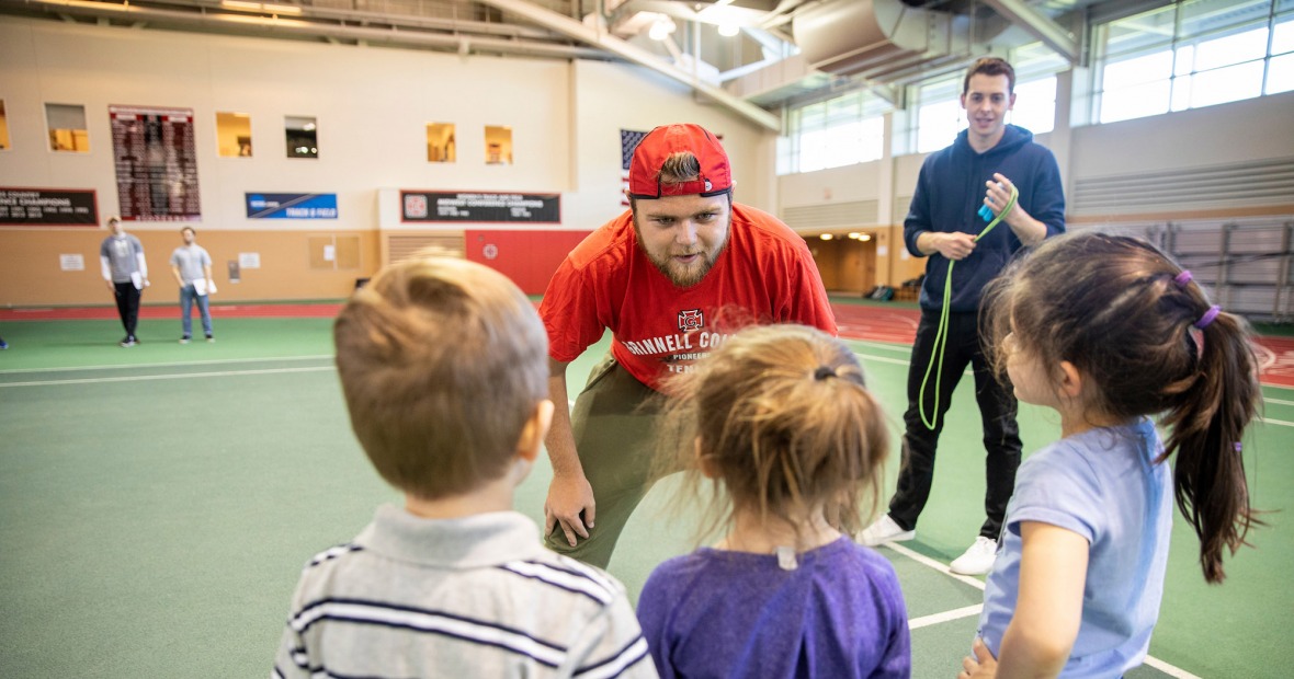 Coaching student talks to three young athletes